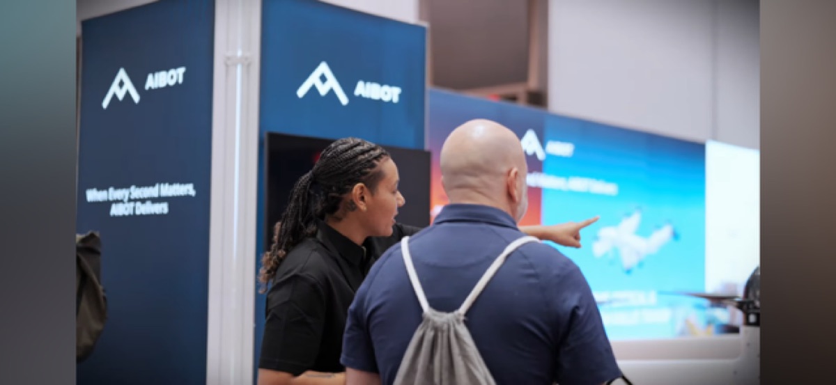 Lauren Session discussing an AIBOT aircraft display with a visitor at an aerospace expo