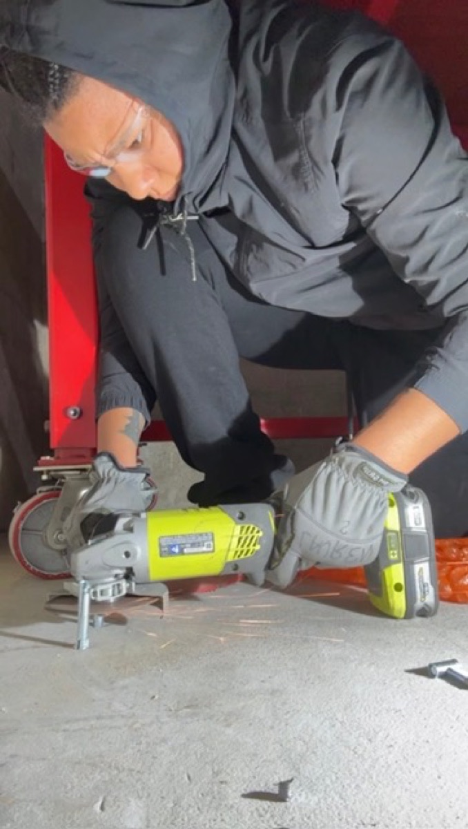 Lauren Session safely operating a handheld grinder while wearing eye protection and gloves